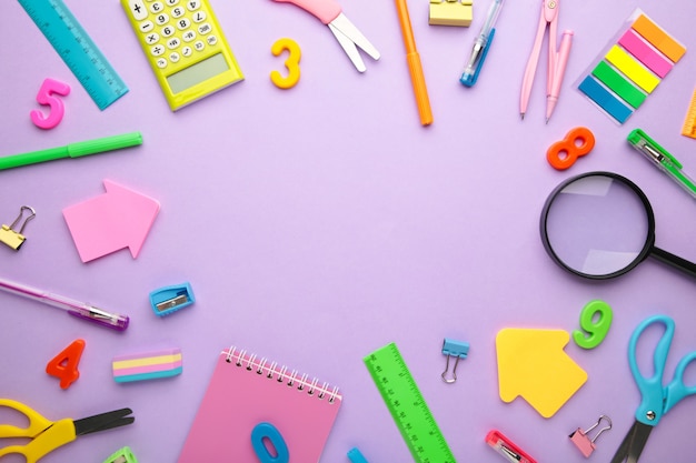 Photo school supplies on purple background. back to school concept. top view.