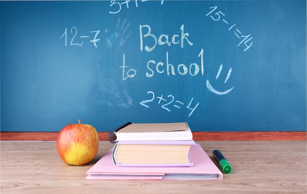 School supplies on table on blackboard background