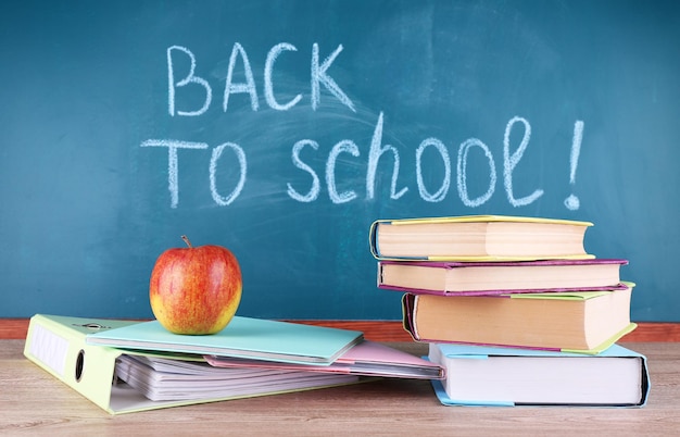 Photo school supplies on table on blackboard background