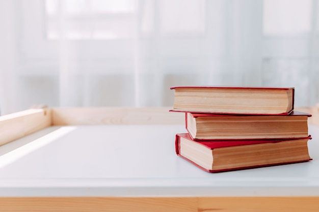 School supplies on white table. Big red books on the table.