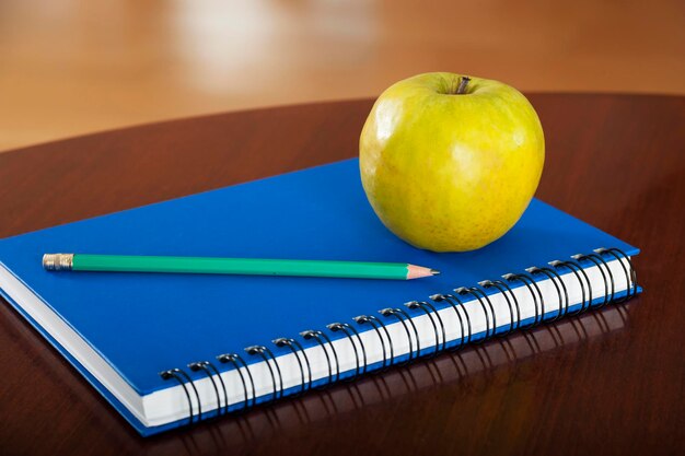 School supplies with apple on wooden table