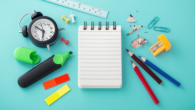 School supplies with blank notebook and clock