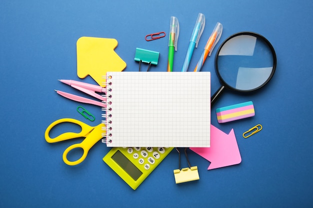 School supplies with notebook on blue background. Back to school. Flat lay. Top view