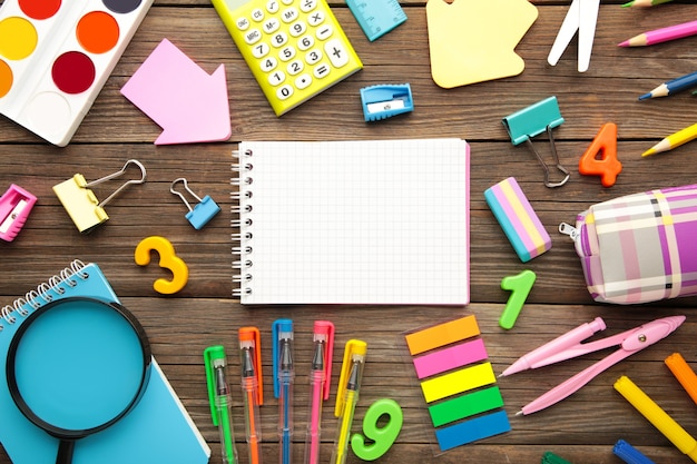 School supplies with notebook on grey wooden background. Back to school. Flat lay. Top view