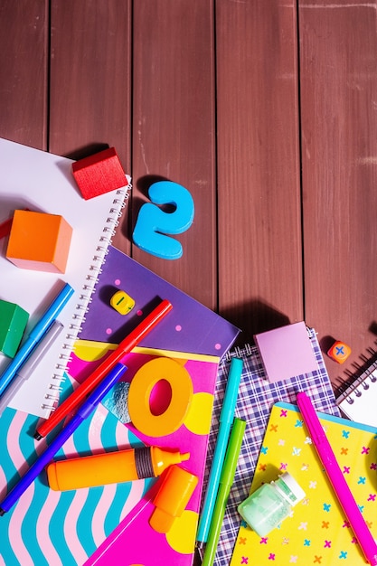 Photo school supplies on wooden boards background. album, notebooks, felt-tip pens, brushes, palette, wooden cubes and numbers. fashion hard light, dark shadow, top view