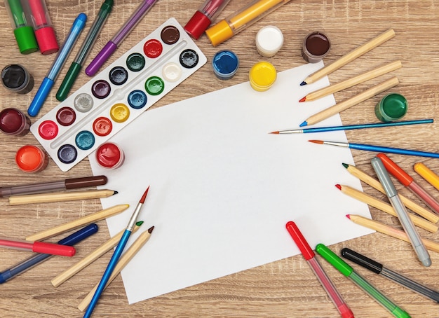 School supplies on a wooden desk with white paper background