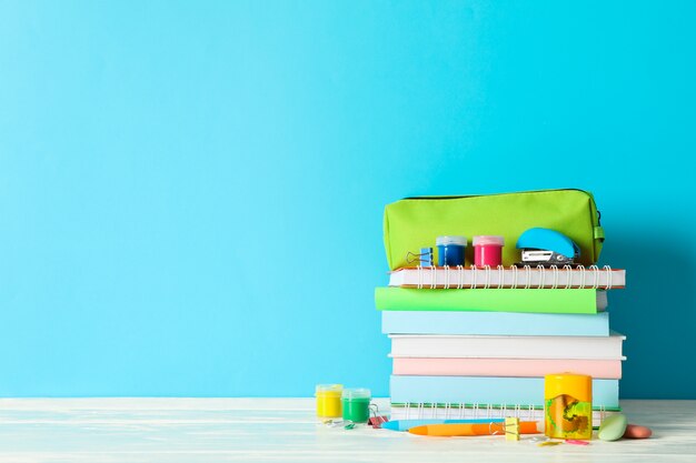 School supplies on wooden table against color