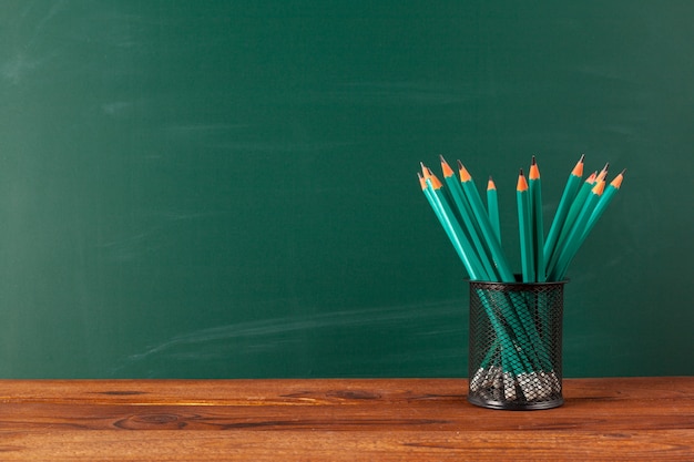 School supplies on a wooden table and blackboard background with copyspace