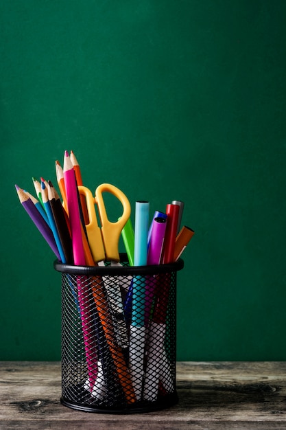 School supplies on a wooden table and blackboard background