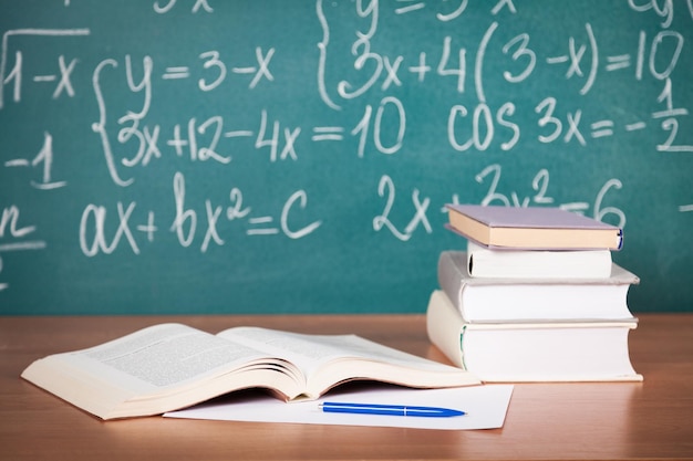 School textbooks on a desk in front of blackboard