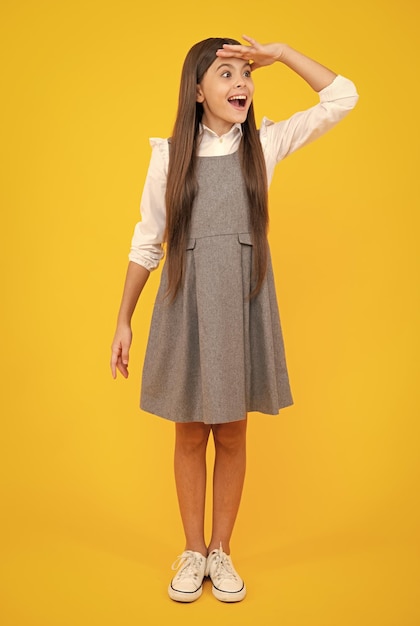 学校の制服ブルネットの十代の少女の全身写真は、黄色の背景に分離されたカジュアルな服を着ています