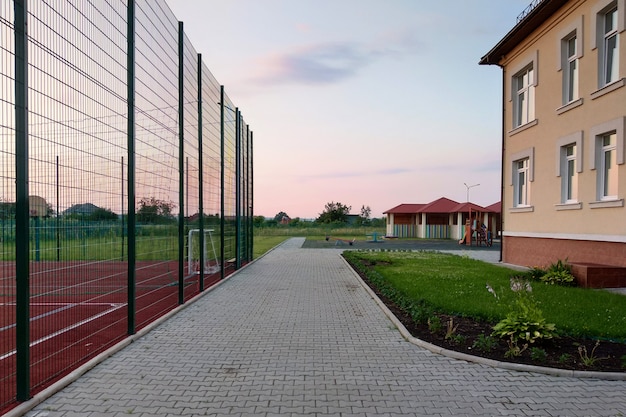 School van voorschoolse bouwwerf met basketbalveld omringd met hoge beschermende omheining.