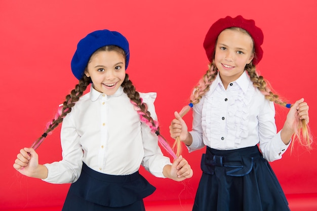 School vriendschap Op dezelfde golf Schoolmeisjes dragen formeel schooluniform Kinderen mooie meisjes lang gevlochten haar Fancy stijl Kleine meisjes met vlechten klaar voor school School mode concept