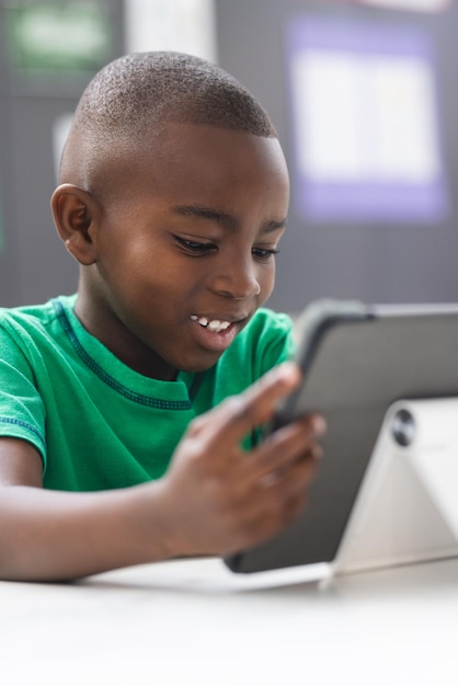 in school young african american boy is focusing on a tablet in the classroom