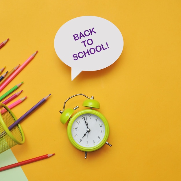 Schoolachtergrond met wekker, potloden en papier