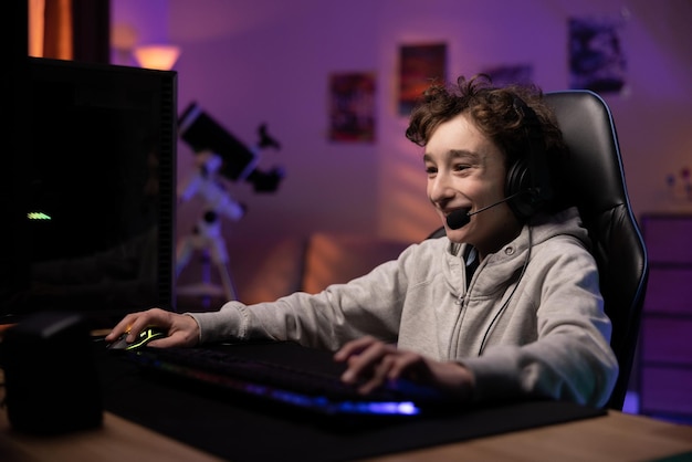 Schoolage child pro gamer spends time in front of the monitor playing computer games laughing boy