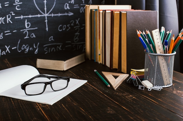 Schoolbank in de klas, met boeken op de achtergrond van krijt bord met schriftelijke formules