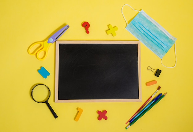 Schoolbenodigdheden en een lege lei op een witte geïsoleerde muur