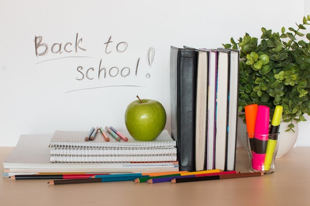 Schoolbenodigdheden met appel en plant op tafel