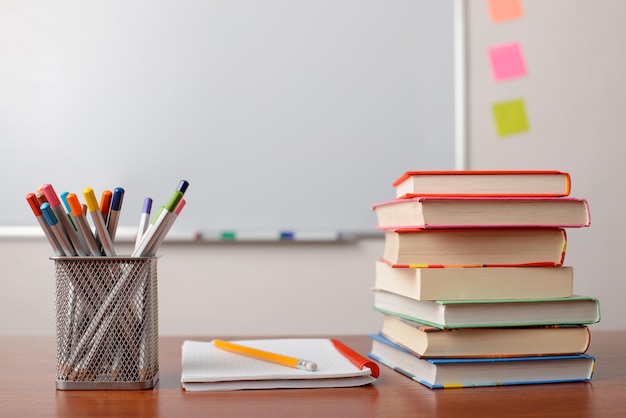 Schoolbenodigdheden op een bureau Stapel boeken, notitieboekje en veel potloden die op tafel liggen