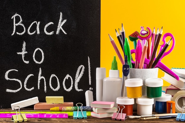 Schoolbenodigdheden op een tafel voor schoolbord met tekst "Terug naar school"