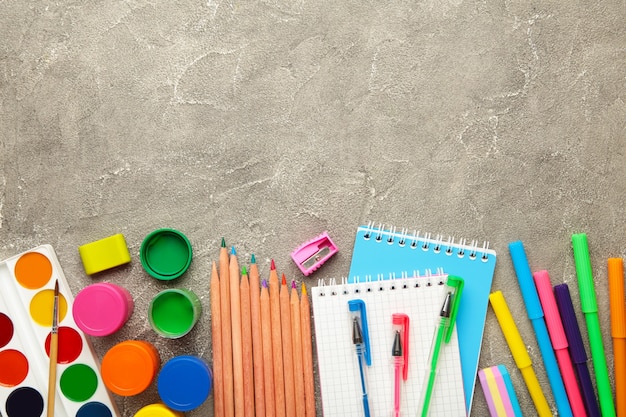 Schoolbenodigdheden op grijze betonnen achtergrond met kopieerruimte. Terug naar schoolconcept. Bovenaanzicht.
