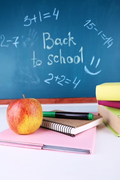 Schoolbenodigdheden op tafel op schoolbordachtergrond