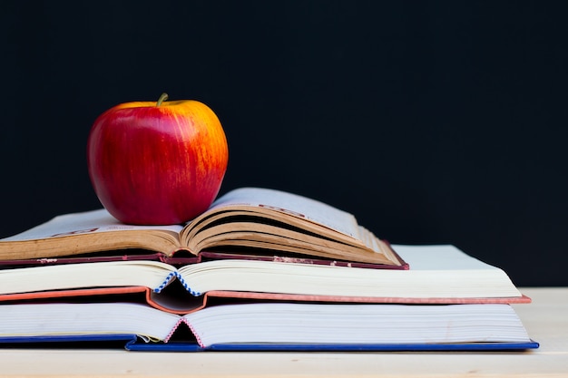 Schoolboeken en appel tegen bord