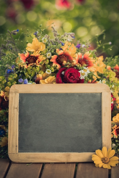 Schoolbord leeg en bloemen op houten tafel