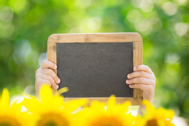 Schoolbord leeg in handen tegen lente groene achtergrond