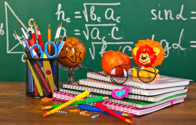 schoolbord met pennenbakje en schoolspullen op tafel