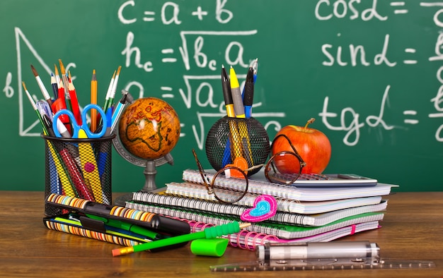 schoolbord met pennenbakje en schoolspullen op tafel