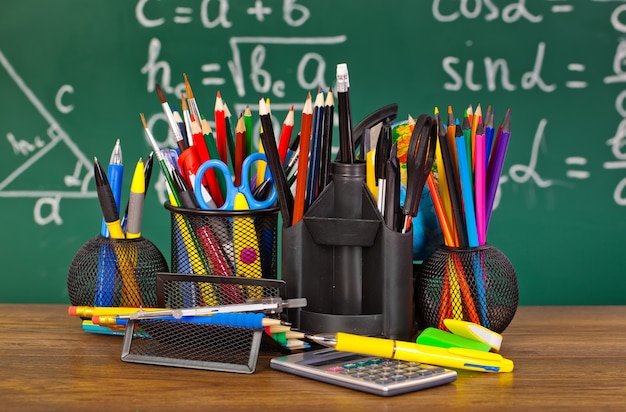 Schoolbord met pennenbakje en schoolspullen op tafel