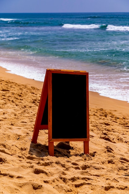 Schoolbord op zandstrand aan de oceaan