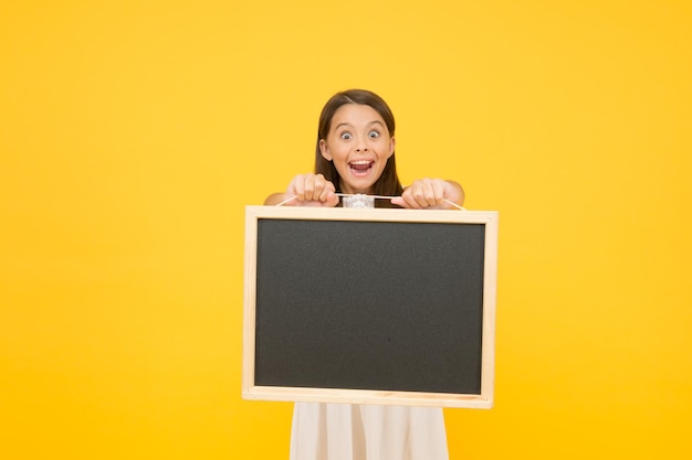 Schoolbord voor informatie Leeg schoolbord Lees dit Iets wat u moet weten Gelukkig lachend meisje houdt schoolbord Klein kind met leeg schoolbord Advertentie promotie kopieerruimte