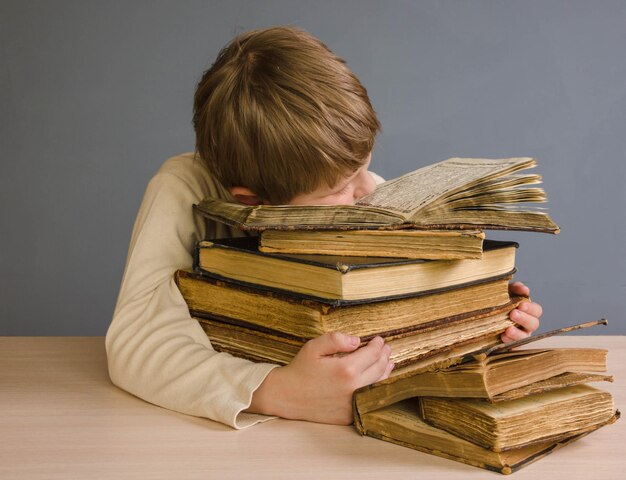 A schoolboy boy hugs a stack of books