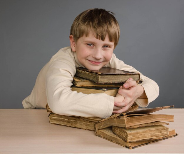 A schoolboy boy hugs a stack of books