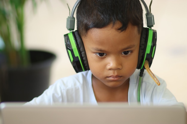 男子生徒は自宅のラップトップでオンラインで勉強します。教師とオンラインで通信します。コンピューターで学校からのレッスンを教えます。遠隔教育に参加します。