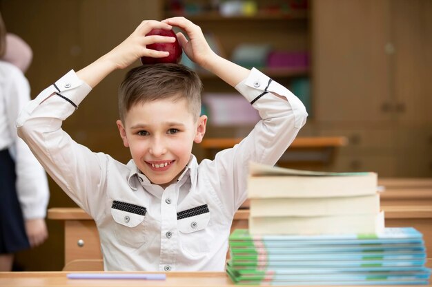 机に向かっている男子生徒 教室で本とリンゴを持っている男子生徒 中等学校 学校に戻る