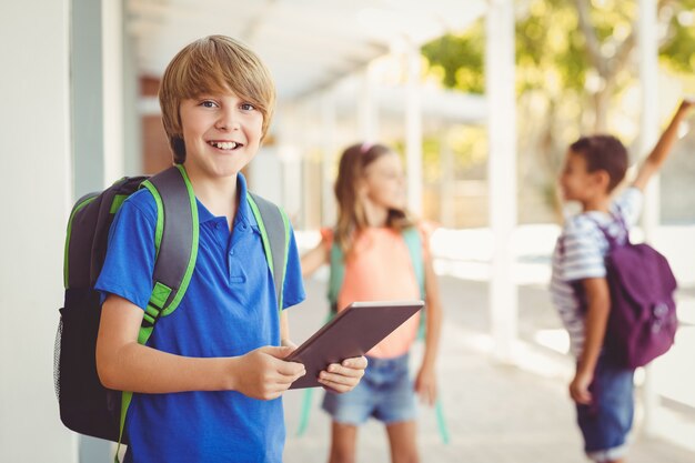 Школьник держит цифровой планшет в школьном коридоре