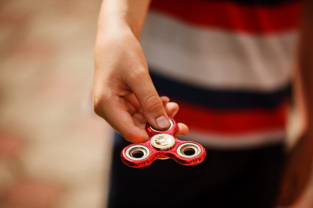 Schoolboy holds a spinner fidget in his hands. Trendy and popular toy for children and adult.