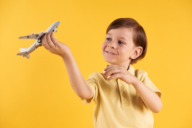 Schoolboy is playing with model airplane.