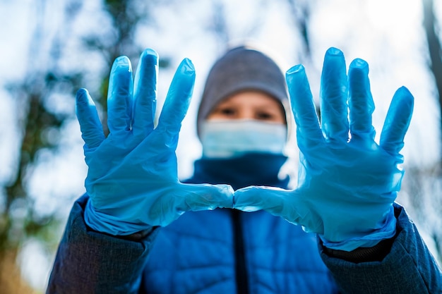 Schoolboy in medical rubber gloves and face maskTeenage shows two palms in stop sign in front of camera Stop the coronavirus Pandemic COVID19 corona virus epidemic infection quarantine virus