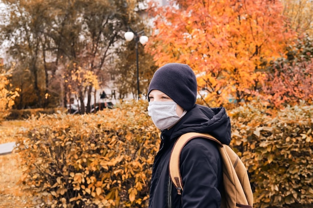 Lo scolaro con una maschera protettiva va a scuola lungo una strada vuota nuova normalità