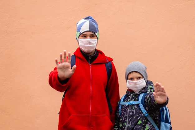 A schoolboy in a protective mask shows his hand STOP