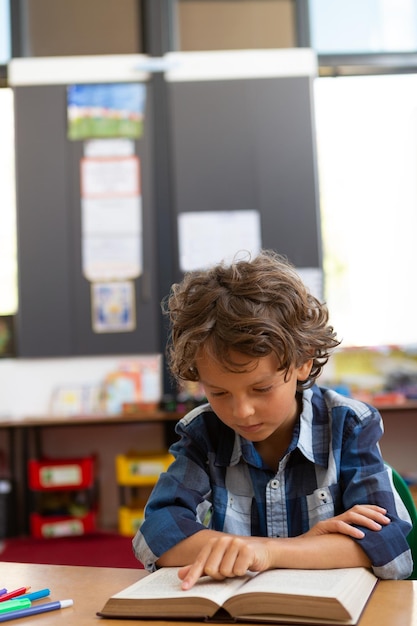 Schoolboy reading a book in the classroom