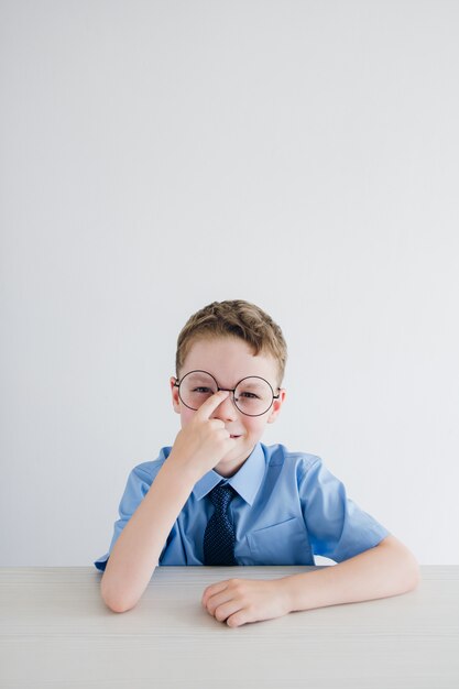 Schoolboy in school uniform and glasses sitting at the Desk