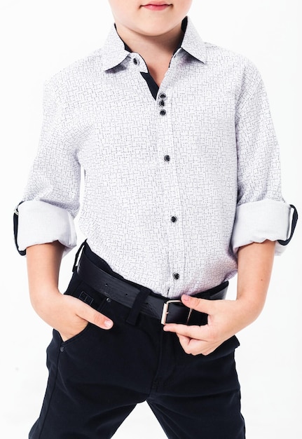 Schoolboy in a school uniform on a white background The boy demonstrates the belt in black trousers Vertical photo