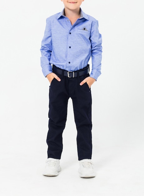 Schoolboy in a school uniform on a white background The boy demonstrates a shirt trousers a belt and sneakers Vertical photo