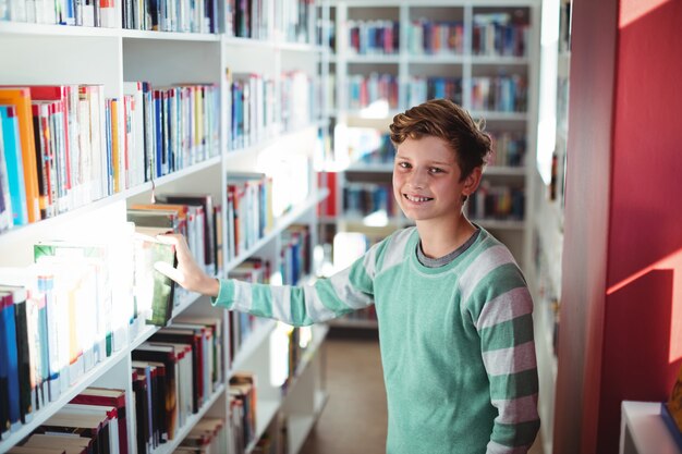 Schoolboy selecting book in library